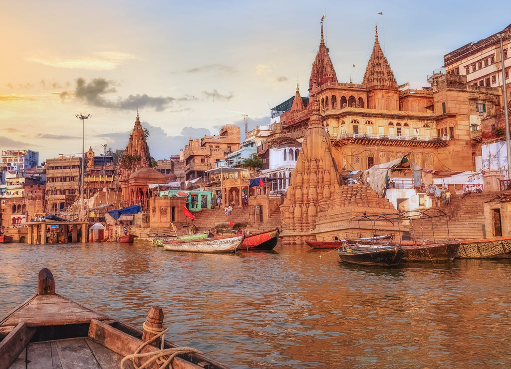 Varanasi Ganges river ghat with ancient city architecture as viewed from a boat on the river at sunset