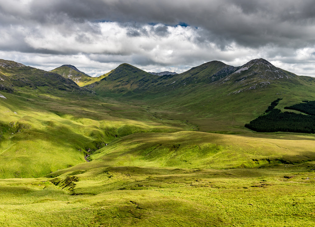 The view of a green valley in Ireland's Connemara National Park with the Twelve Bens Mountains in the background