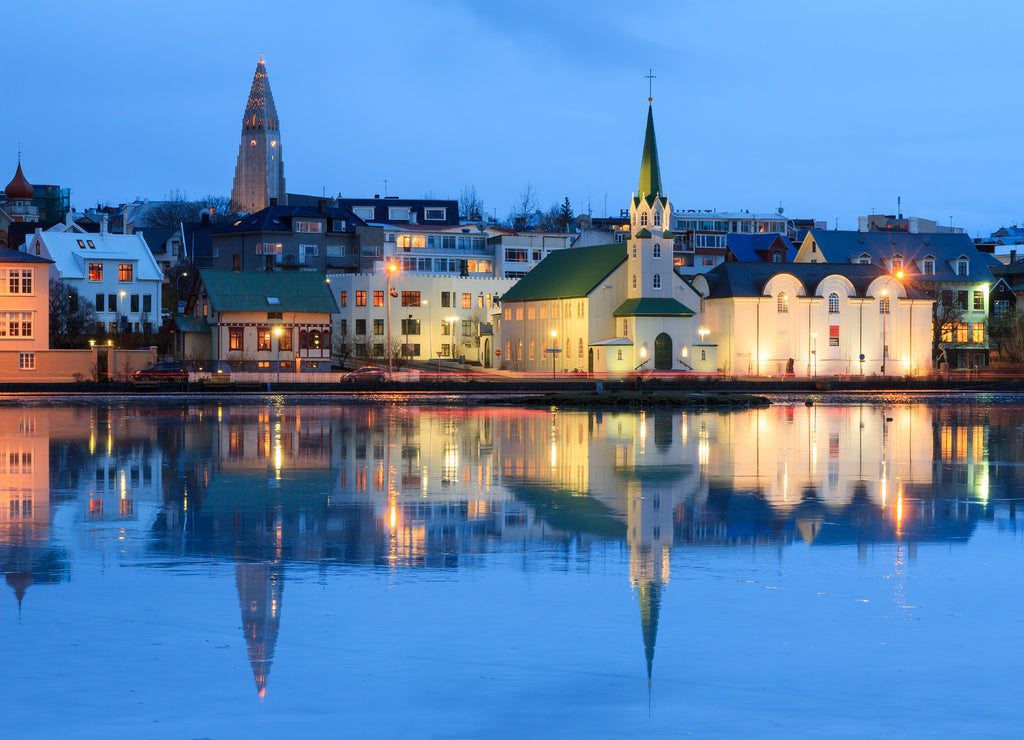 Beautiful reflection of the cityscape of Reykjavik in lake Tjornin at the blue hour in winter