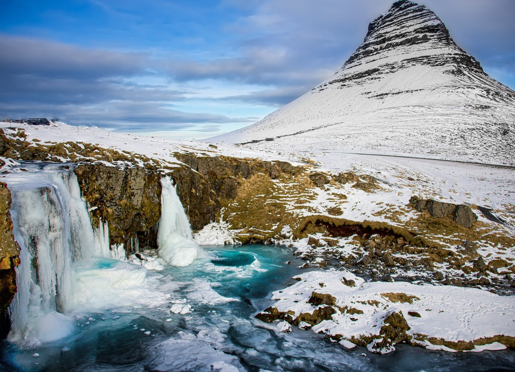 Frozen waterfall with the mountain Kirkjufell in the Snæfellsnes peninsula in Iceland