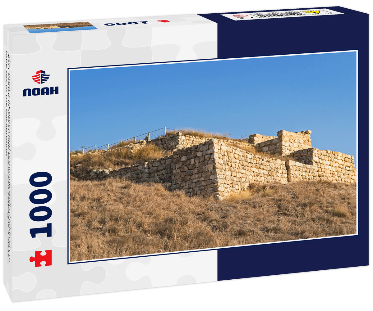 The stone city gates and retaining wall of biblical era Tel Lachish in Israel with the moon setting in a clear blue sky in the background