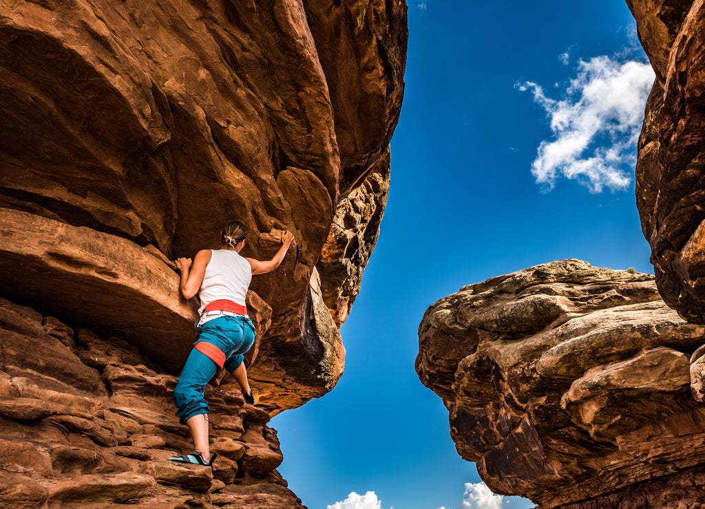 Girl Climber practicing bouldering on a beautiful red rock in Canyonlands Utah USA