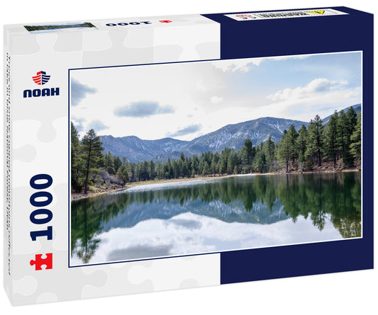 Trees and snow capped mountains reflected in lake in Dixie National Forest, Utah