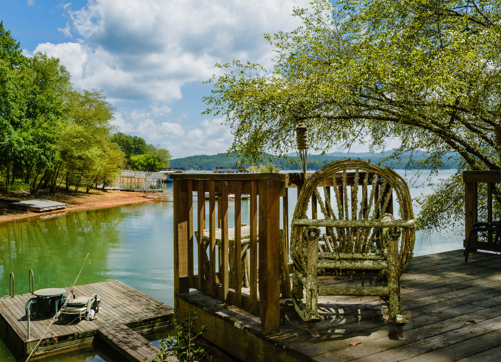 Rustic rocking chair on bank of lagoon in summer. Tennessee, USA