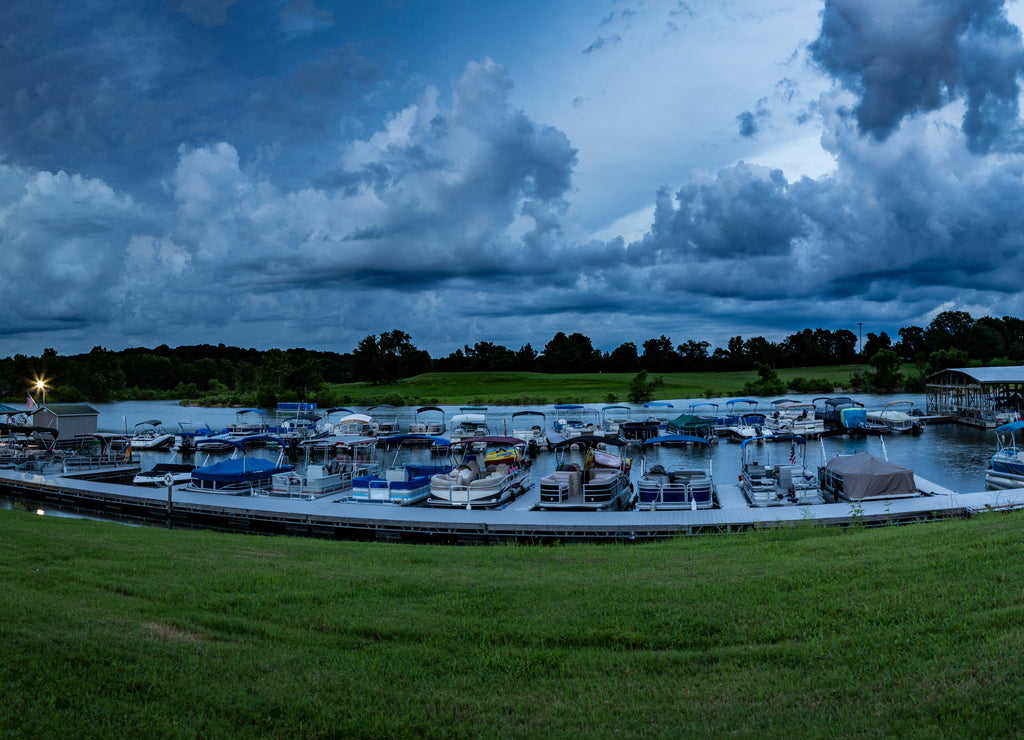 Boats and pontoons docked on Barren River Lake State Park Marina, Scottsville Kentucky during sunset with dramatic clouds over them