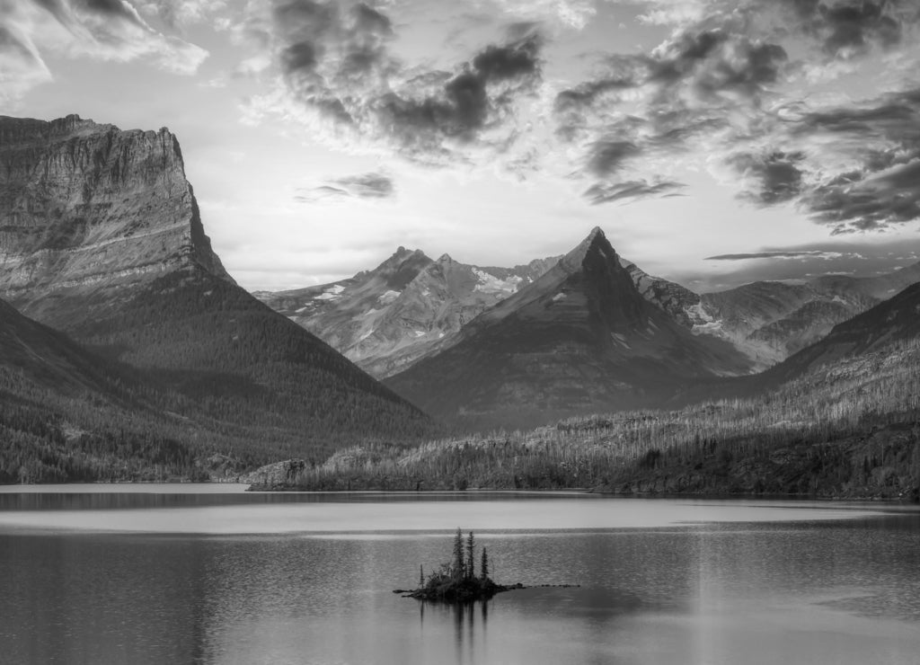 Beautiful Panoramic View of a Glacier Lake with American Rocky Mountain Landscape in the background. Dramatic Colorful Sunrise Sky. Taken in Glacier National Park, Montana, United States in black white