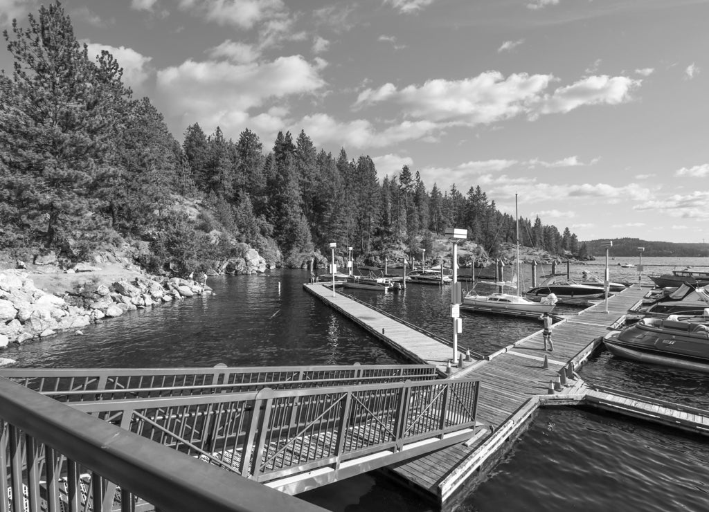 Boats, wave runners and watercraft docked at a marina along Tubbs Hill on Lake Coeur d'Alene in Coeur d'Alene, Idaho USA in black white