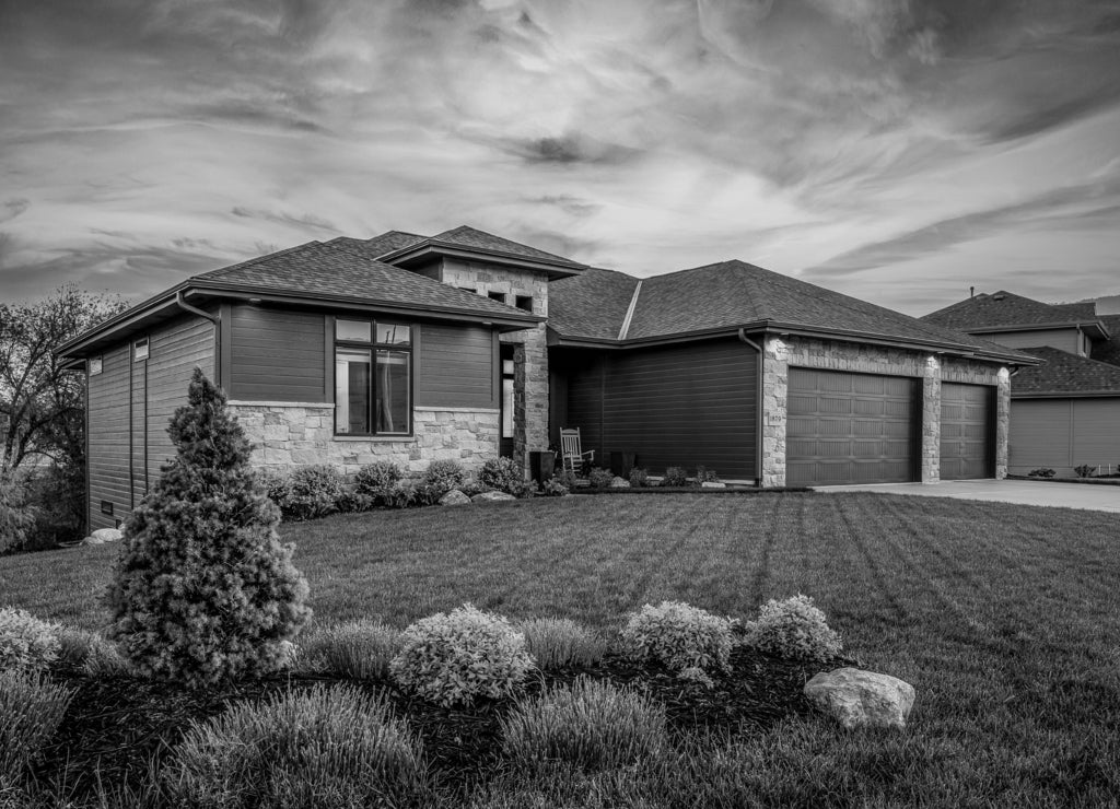 Luxury home during twilight golden hour with pink and purple sky and lush landscaping in Nebraska USA in black white