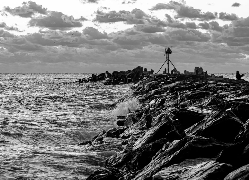 Waves crashing onto the breakwater at Manasquan Inlet at Sunrise, New Jersey in black white