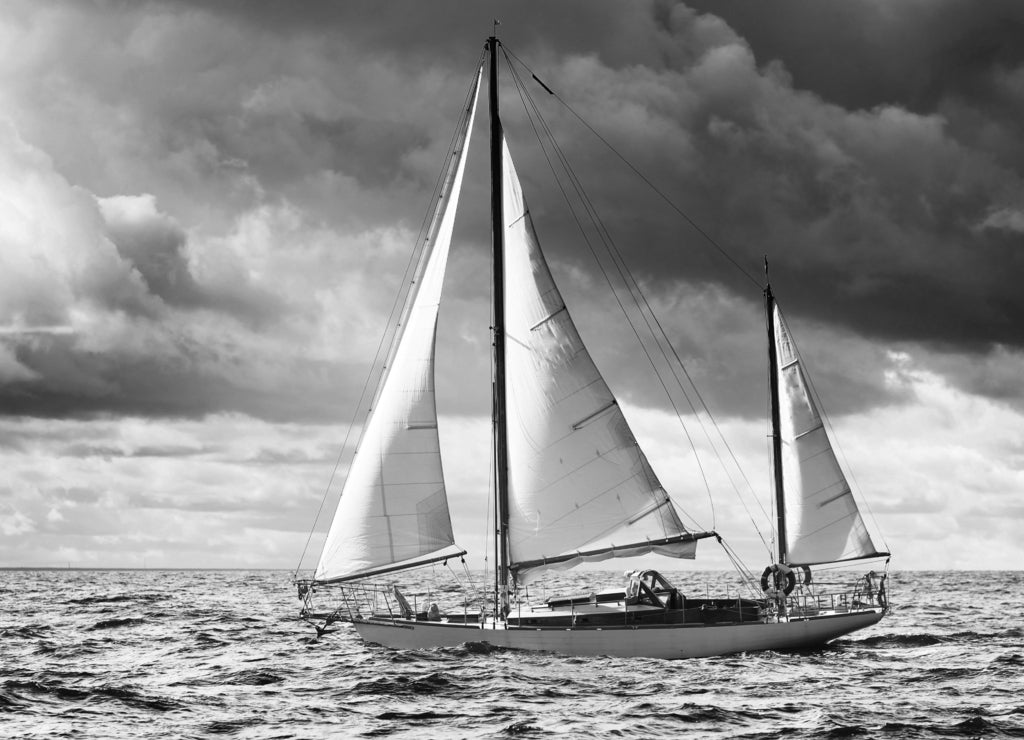 Vintage wooden sailboat (yawl) sailing in an open sea, coast of Maine USA in black white