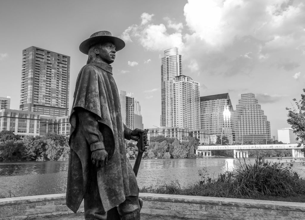 Stevie Ray Vaughan statue in front of downtown Austin and the Co, Texas in black white