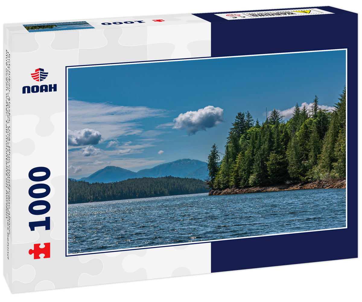 Ketchikan, Alaska, USA: Blue cloudscape above landscape of green forests on island shorelines behind blue ocean water. Tall mountains on horizon