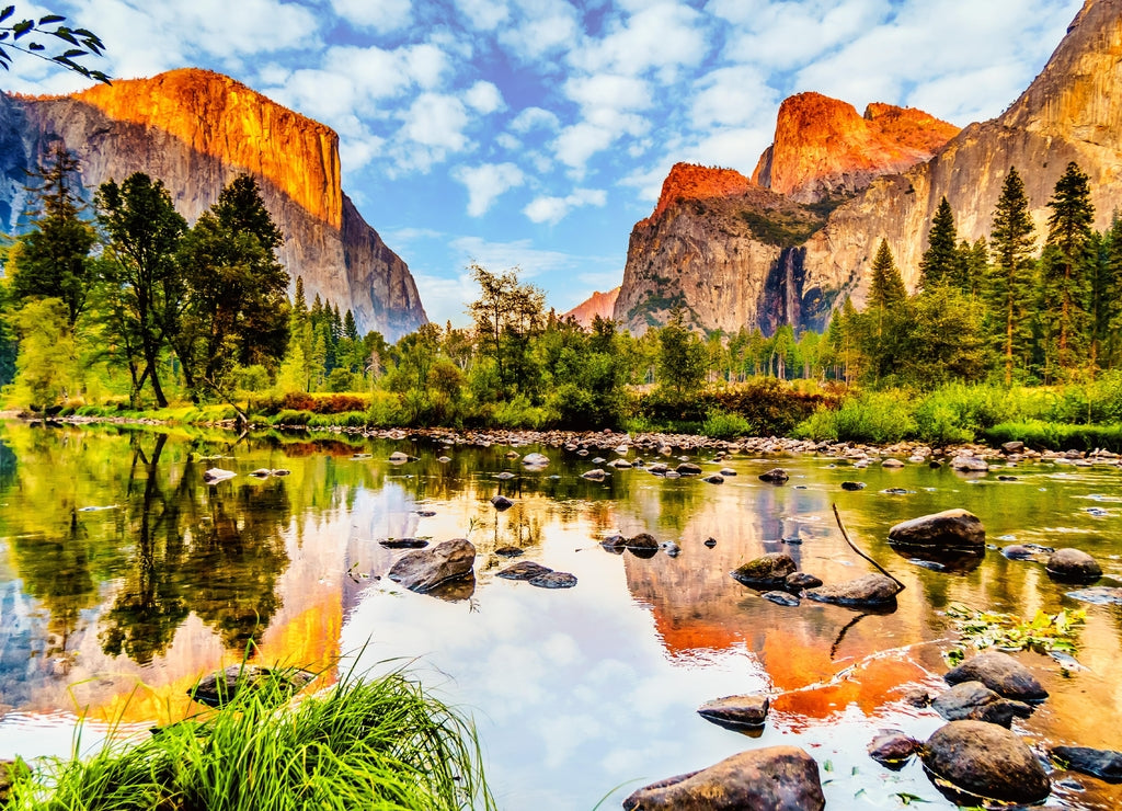 Sunset glow over El Capitan on the left and Cathedral Rocks, Sentinel Rock and Bridalveil Fall on the right and reflecting in the calm water of Merced River in Yosemite National Park, California, USA