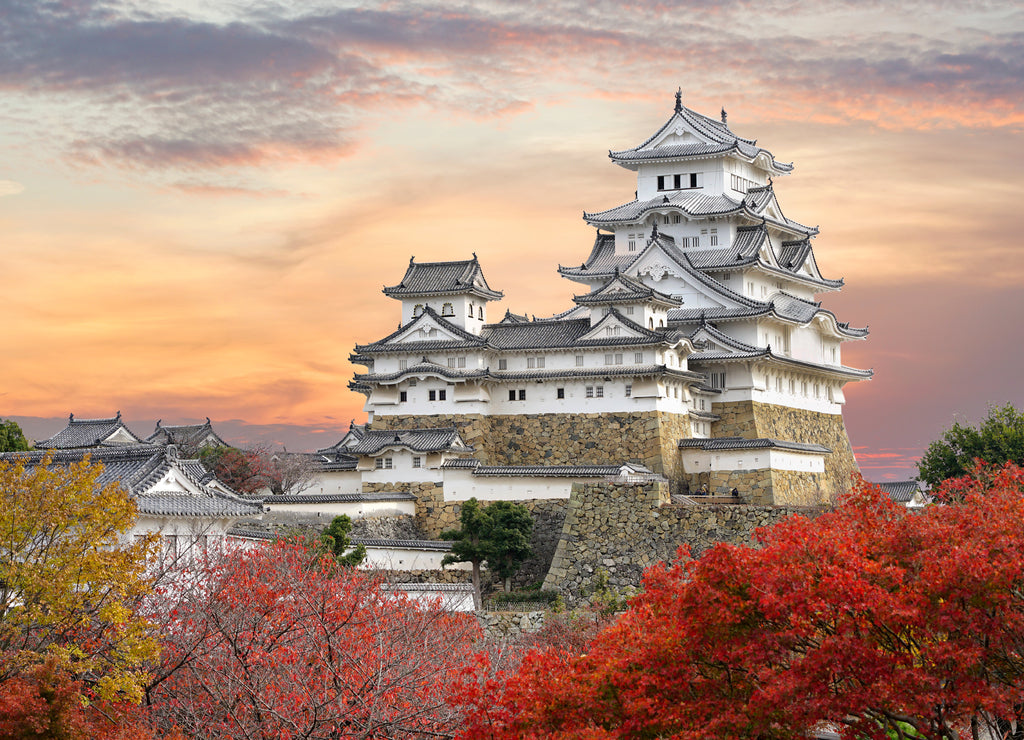 Himeji Castle and red maple leaves in evening sunlight and twilight sky in Himeji city, Hyogo prefecture of Japan