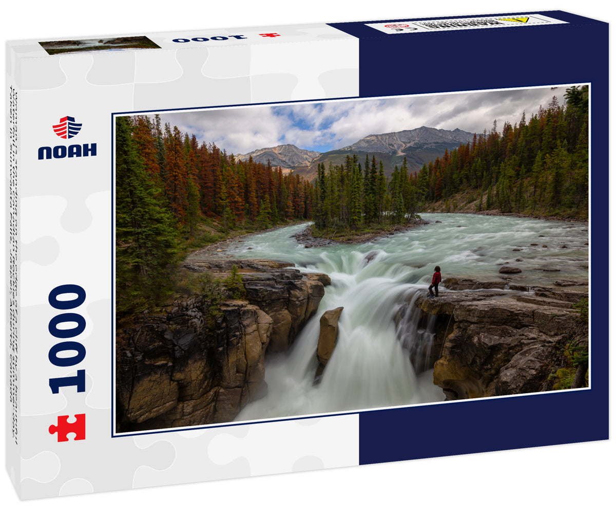 Woman is standing on the edge of a cliff by a beautiful Waterfall in the Canadian Rockies during summer day. Taken in Sunwapta Falls, Jasper, Alberta, Canada