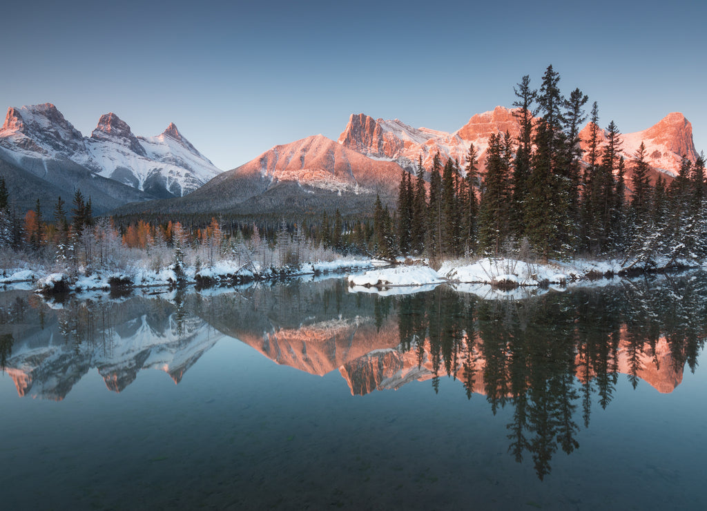 First snow Almost near perfect reflection of the Three Sisters Peaks in the Bow River. Canmore in Banff National Park Alberta Canada Snow-covered winter mountain in a winter atmosphere