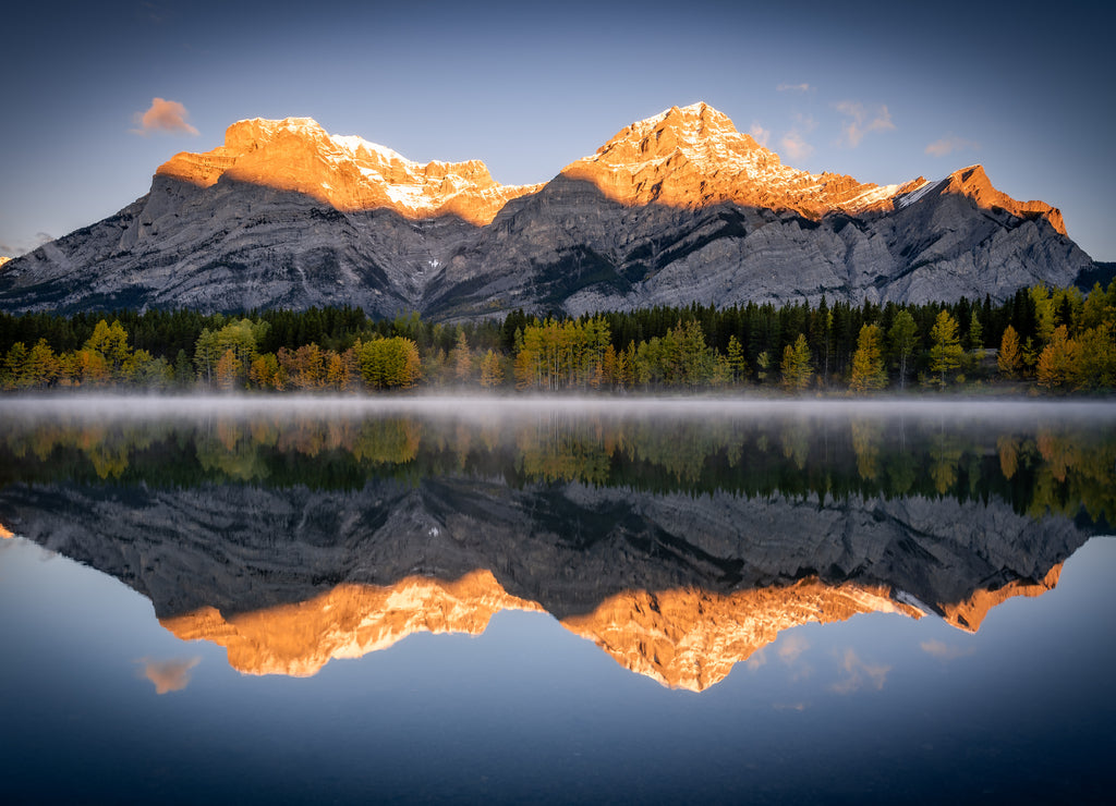 Warm sun glow illuminating Mount Kidd back-dropping and reflecting off of the still Wedge Pond in Kananaskis Country, Canada