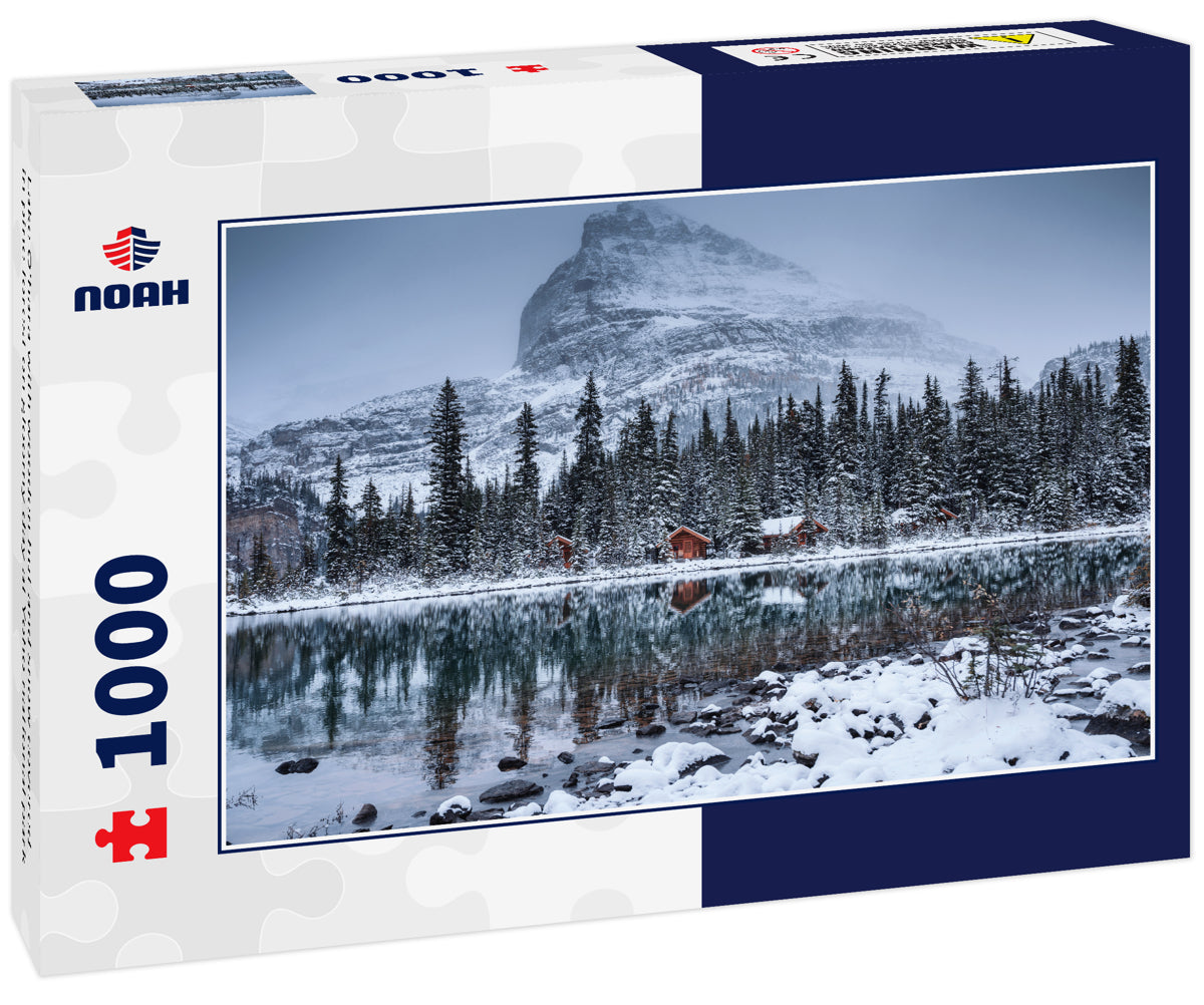 Lake O'hara with wooden hut and snow covered in pine forest on gloomy day at Yoho national park