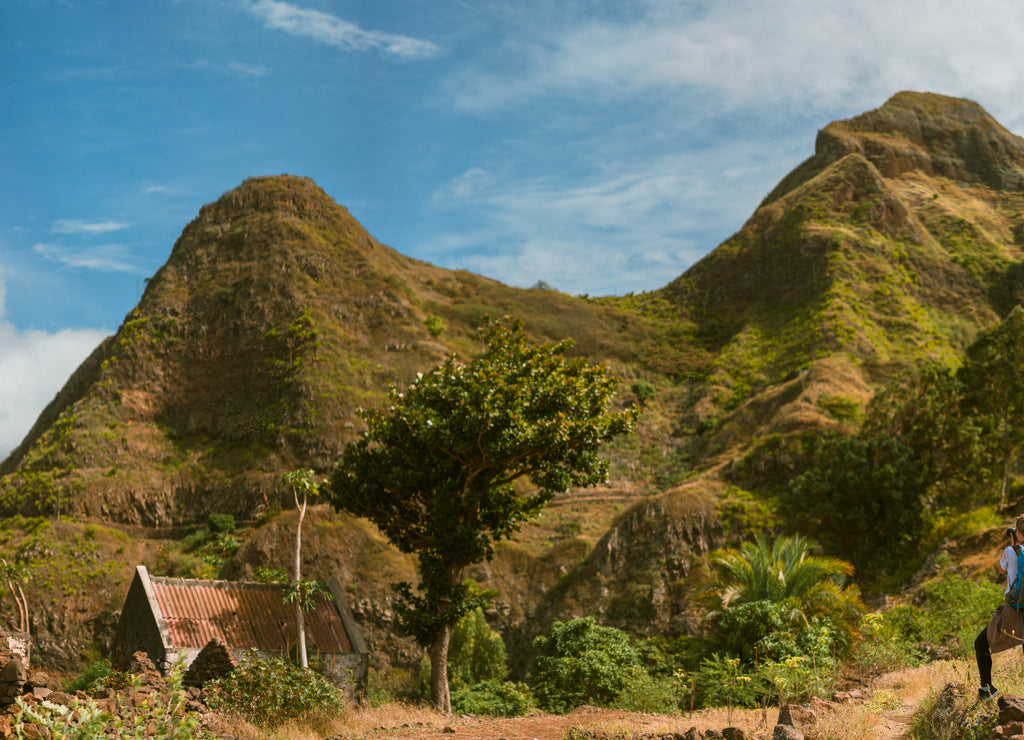 Panoramic view of woman tourist with blue backpack making photo of landscape in Mountains of Santo Antao island, Cabo Verde