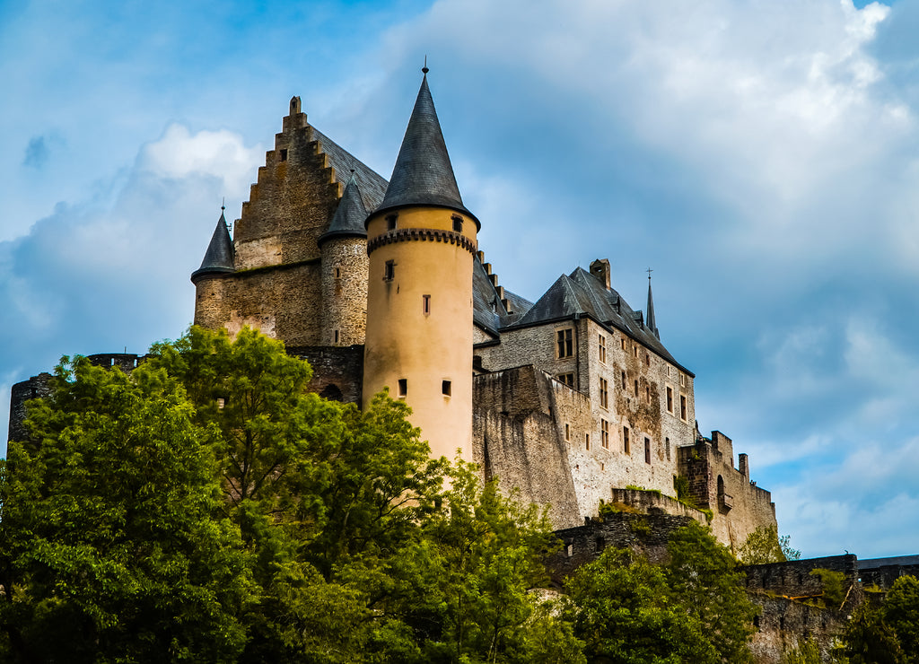 Amazing fairy tale medieval European castle on the hill - Vianden Castle in northern Luxembourg with green trees and cloudy skies in summer