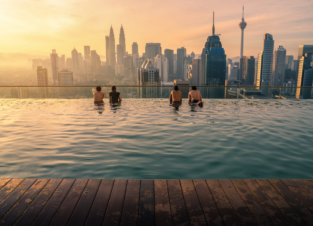 Traveler looking view skyline Kuala Lumpur city in swimming pool on the roof top of hotel at sunrise in Kuala Lumpur, Malaysia