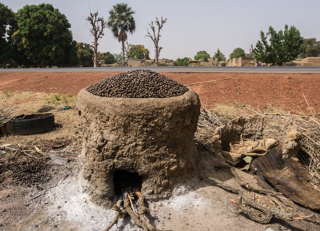 A pile of shea nuts on top of a mud oven being roasted. Mali, West Africa