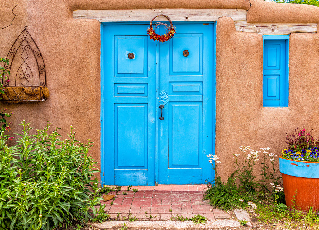 New Mexico traditional colorful architecture with blue turquoise adobe color painted door and ristras decorations at entrance garden