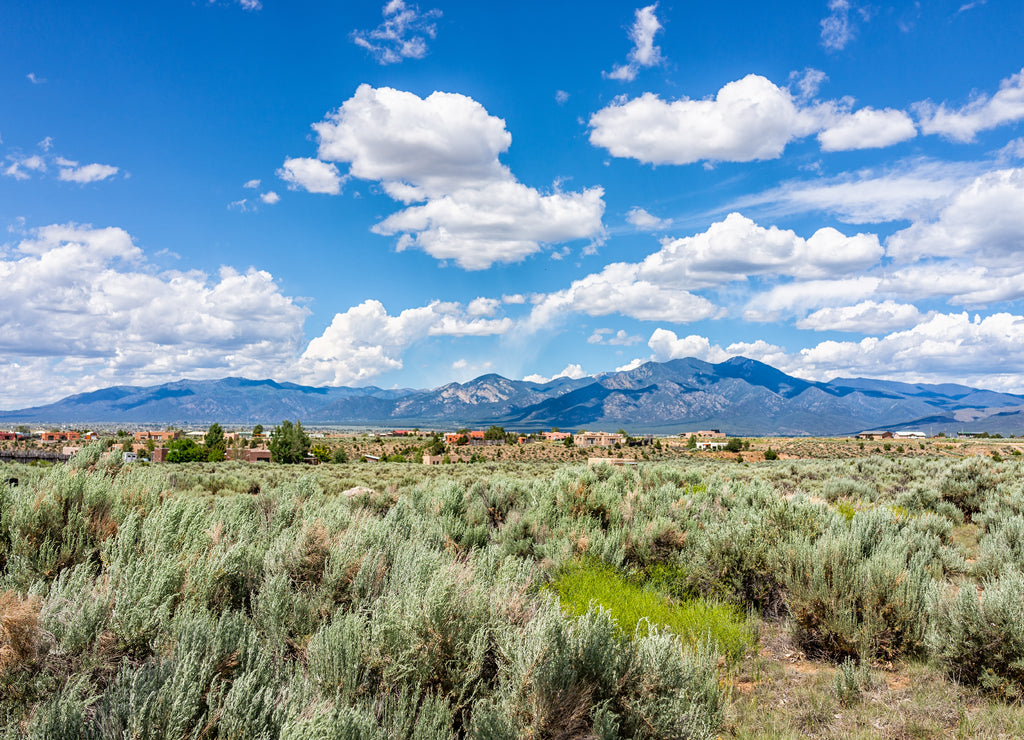 View of Taos Sangre de Cristo mountains view from Ranchos de Taos valley and green landscape in summer with clouds, New Mexico