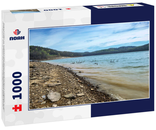 Tygart Lake in Tygart Lake State Park in West Virginia, in the spring with the shoreline filled with sand and rocks leading to the wavy water with the trees and sky filled with clouds