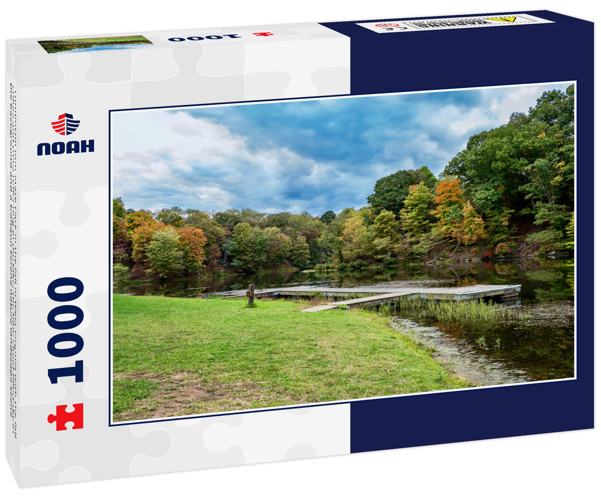 Tomlinson Run State Park in the fall in West Virginia with the fall colors and trees reflecting in the lake, the blue cloud filled sky in the background and a tranquil serene nature landscape scene