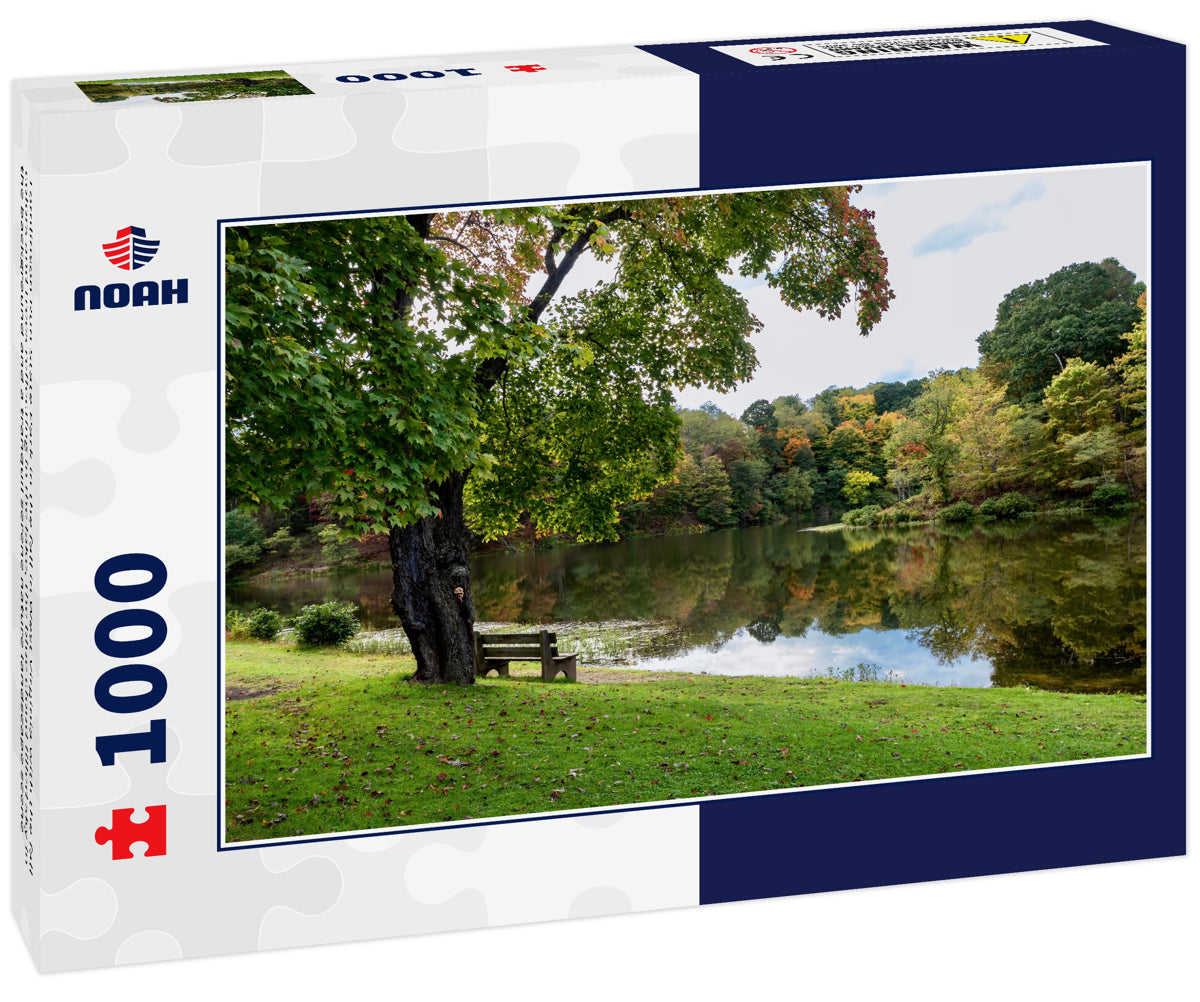 Tomlinson Run State Park in the fall in West Virginia with the fall colors and trees reflecting in the lake, the blue cloud filled sky in the background and a tranquil serene nature landscape scene