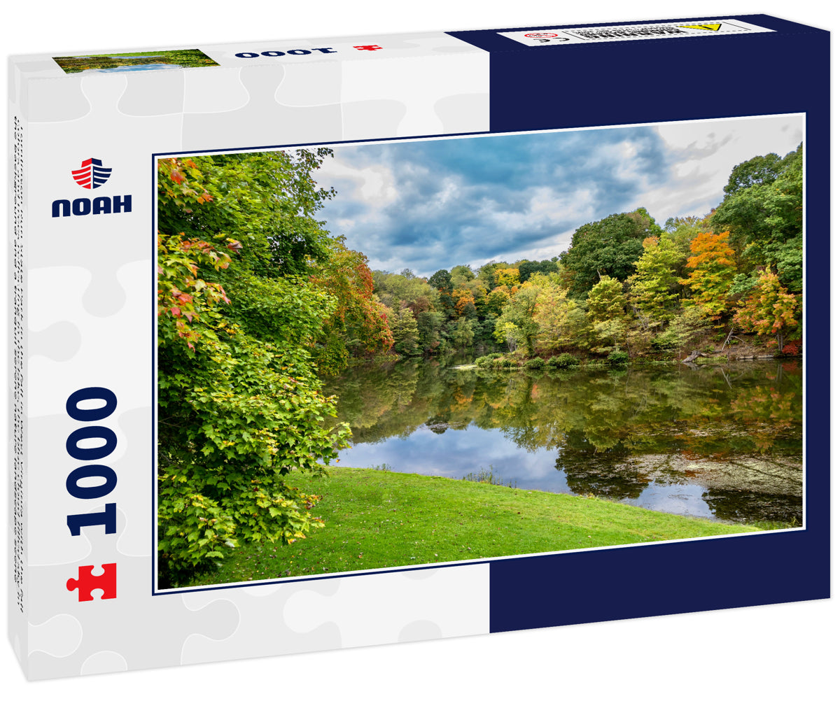 Tomlinson Run State Park in the fall in West Virginia with the fall colors and trees reflecting in the lake, the blue cloud filled sky in the background and a tranquil serene nature landscape scene