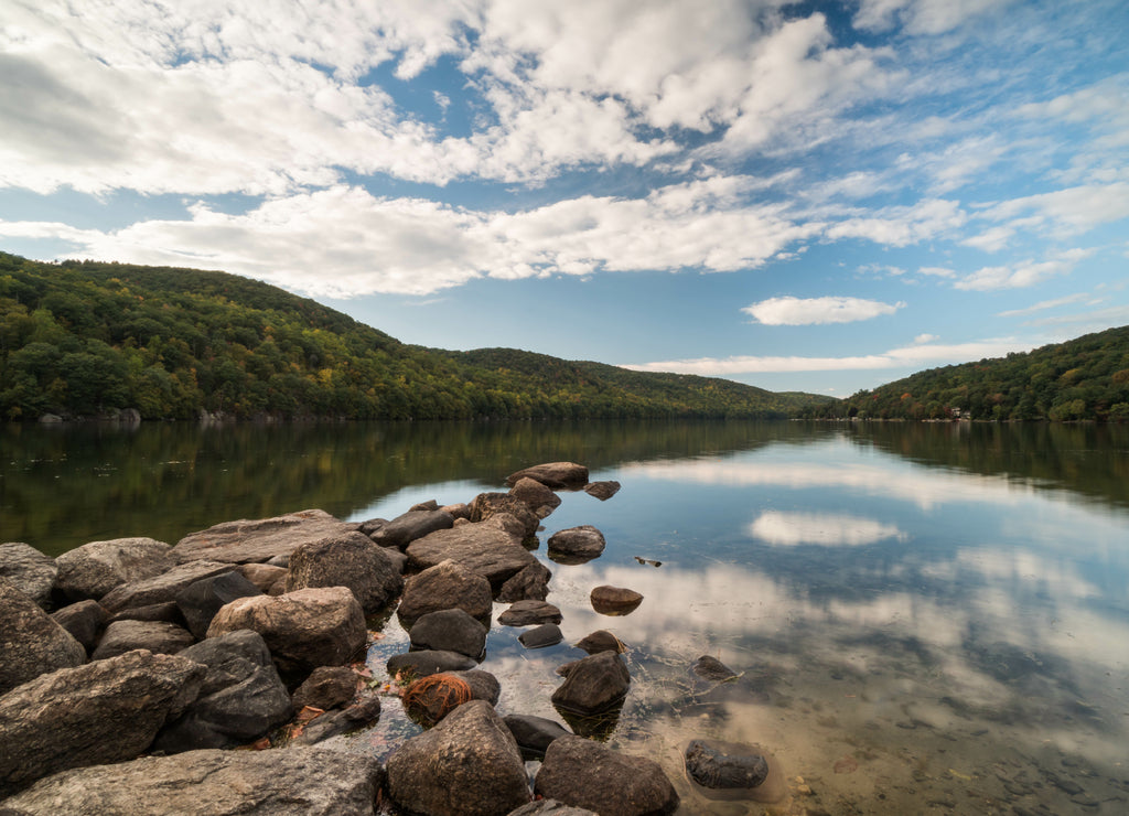 a mountain pond with sky reflection and rocks in the foreground in autumn in New England, Connecticut