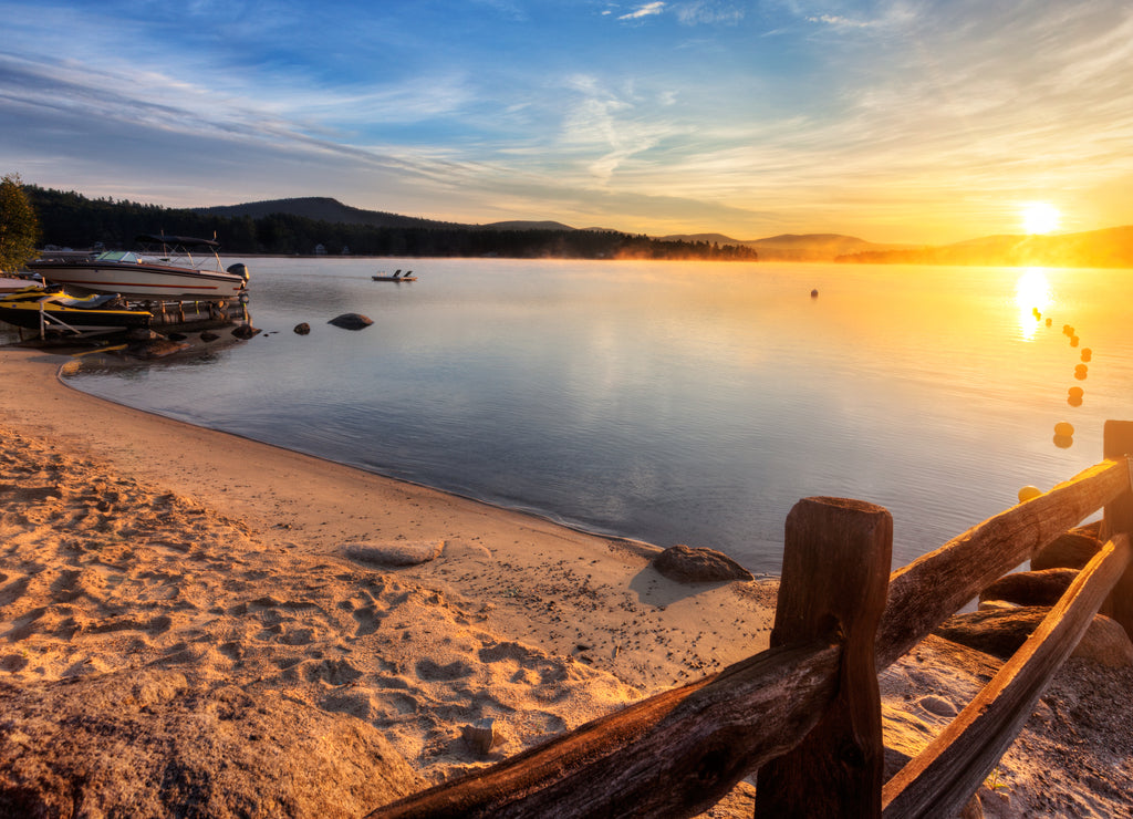 Mist rises from Merrymeeting Lake, as seen from the beach by the marina boat launch, New Durham, New Hampshire right after sunrise on a summer morning