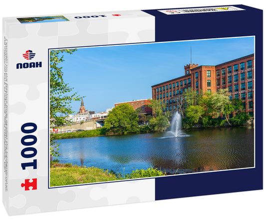 Fountain on the Nashua River against the background of a historic cotton factory building with a clock tower in the old industrial park of Nashua. New Hampshire, USA