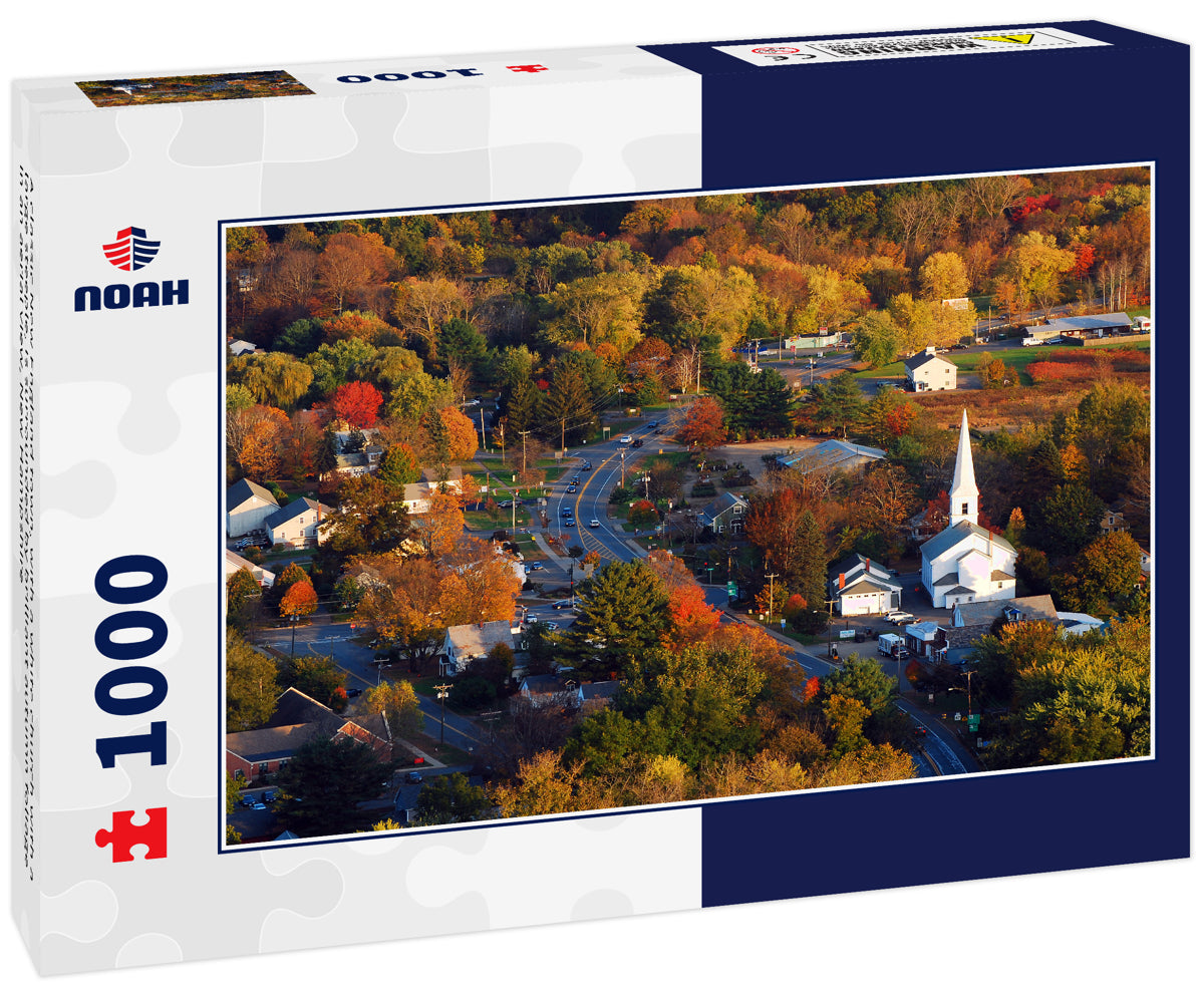 A classic New England town, with a white church with a large steeple, is surrounded by brilliant autumn foliage in an aerial view, New Hampshire