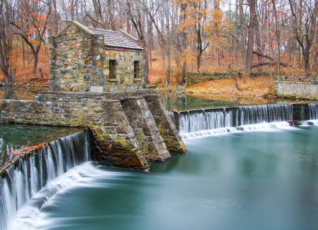 Exterior daytime long exposure stock photo of stone structure on dam and waterfall on Speedwell Lake in Morristown New Jersey in Morris County on overcast fall day