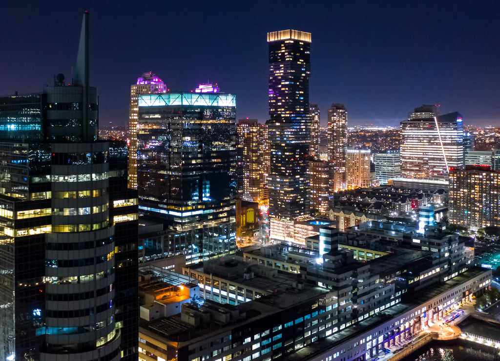 Aerial view of Jersey City skyscrapers by night from a drone flying above Hudson river, New Jersey