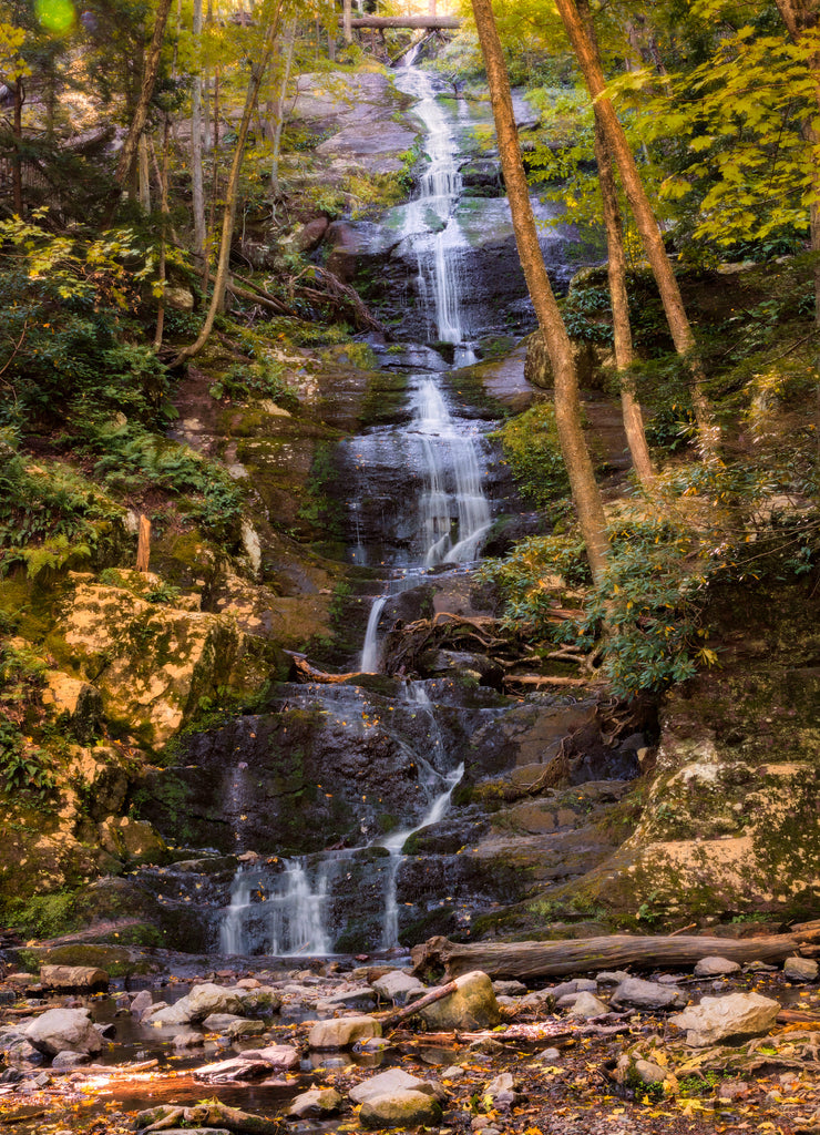 Tall cascading waterfall surrounded by dense foliage changing from summer to autumn. Buttermilk Falls, New Jersey