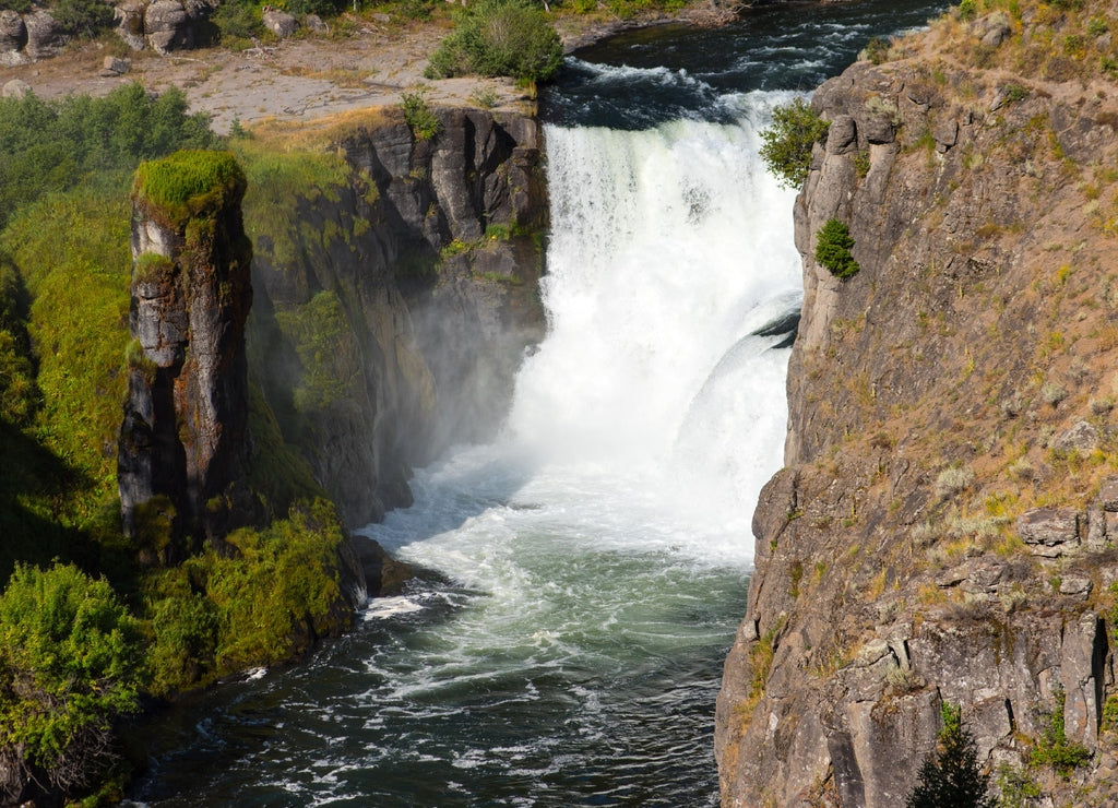 Lower Mesa Falls in the Caribou-targhee National Forest with mist being splashed onto the green foliage and rock tower
