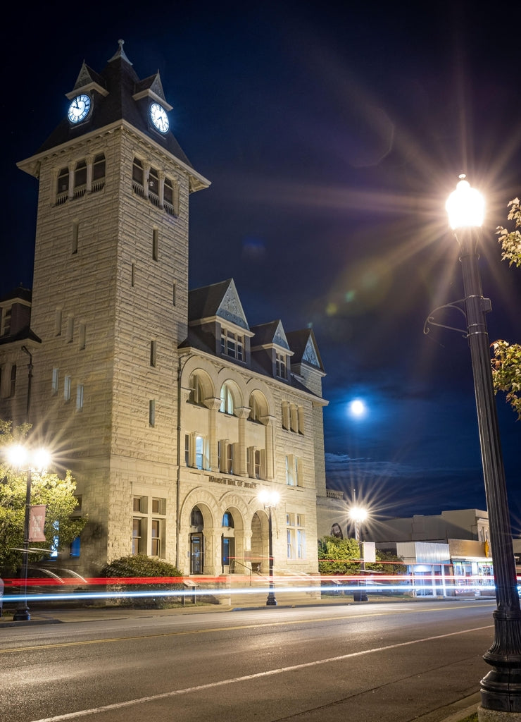 Madison County courthouse in downtown Richmond, Kentucky during early evening with a full moon behind it and night traffic crossing in front of the building