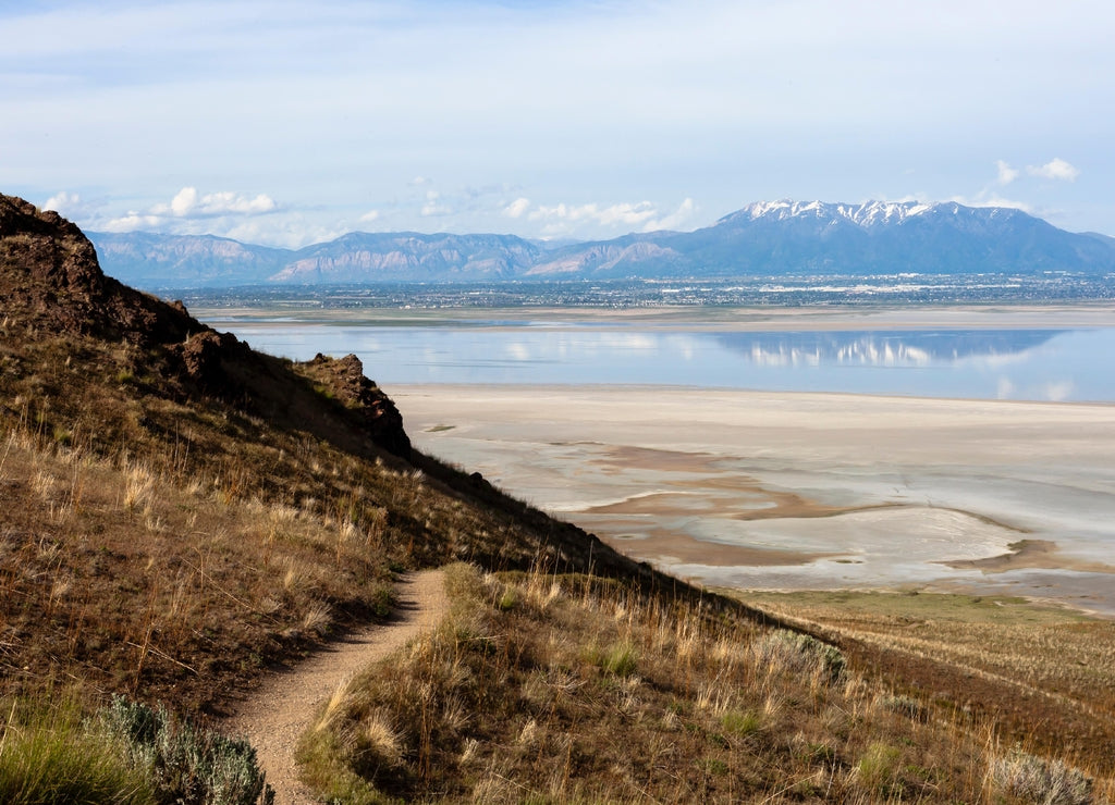 Farmington bay as seen from Antelope island with Wasatch mountain front reflected in water with salt and algae coast line in Davis county, Utah