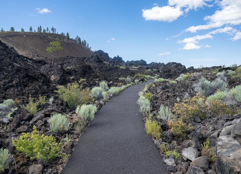 Trail of Molten Lands winds through volcanic rock. Lava Butte in background at Newberry National Volcanic Monument near Bend, Oregon