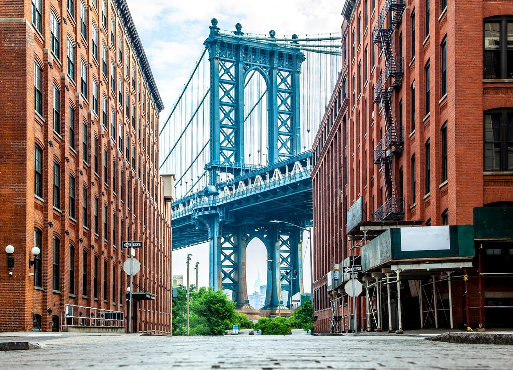 Manhattan Bridge between Manhattan and Brooklyn over East River seen from a narrow alley enclosed by two brick buildings on a sunny day in Washington street in Dumbo, Brooklyn