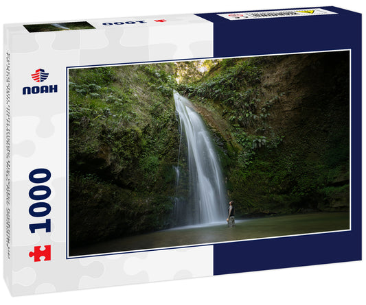 Caucasian man inside the water looking up Te Ana falls in Hawke's Bay, New Zealand