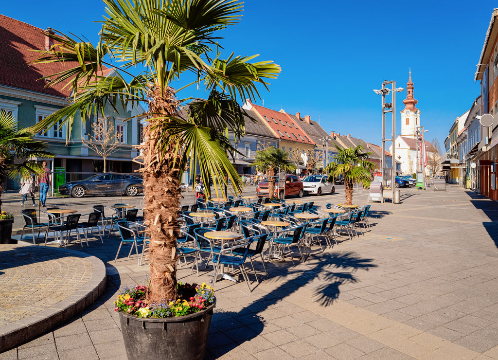 Main square with Palms trees at street cafe and Saint James Catholic Church in town Leibnitz in Styria in Austria. Cathedral architecture