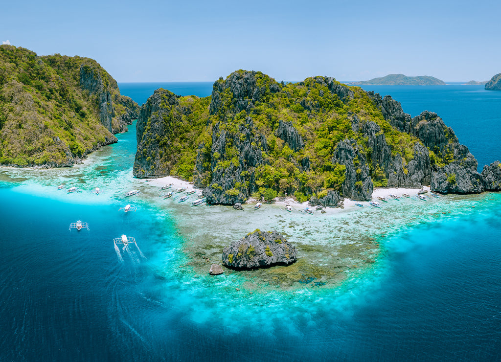 Aerial drone view of tropical Shimizu Island steep rocks and white sand beach in blue water El Nido, Palawan, Philippines