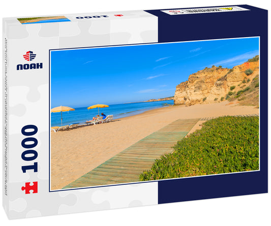 Walkway on sandy beautiful Praia da Rocha beach and two sun umbrellas in distance, Algarve region, Portugal