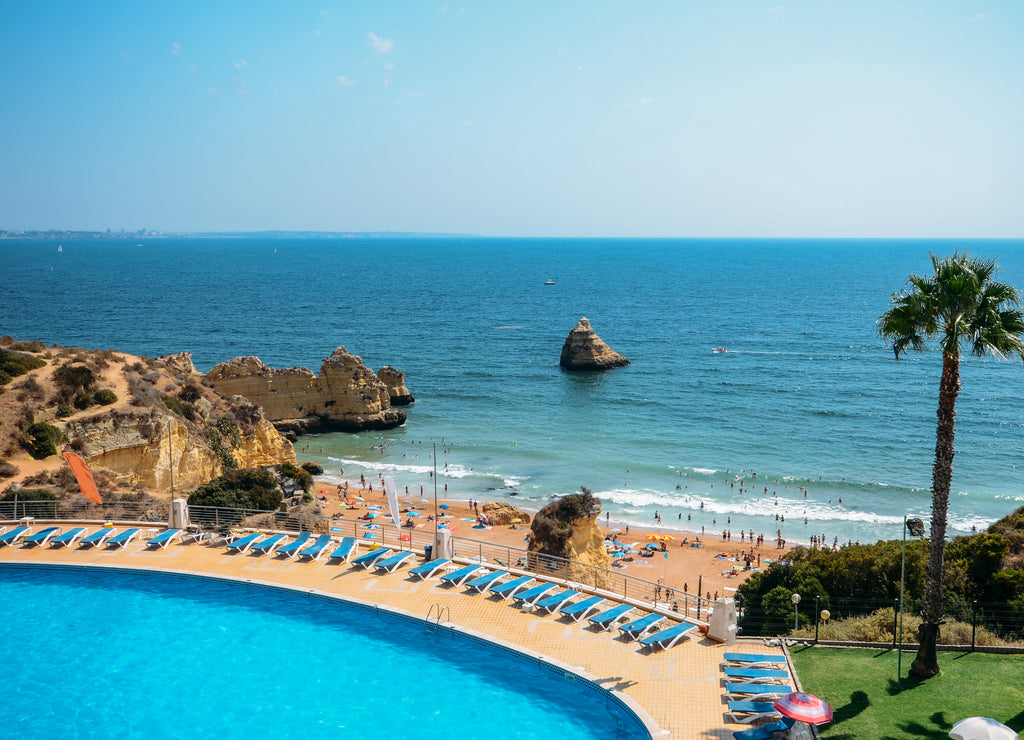 Empty swimming pool overlooking Cova Redonda Beach in Algarve, Portugal during the summer - paradise holiday theme