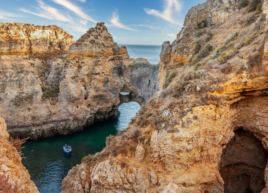 Blue boat on a rocky cavern at Ponta da Piedade, Lagos, one of the most beautiful areas of the beaches in Algarve - Portugal